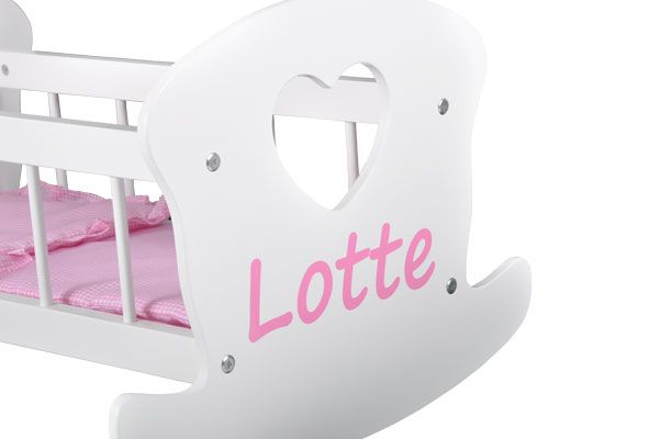 De roze naamsticker op het poppenbedje.